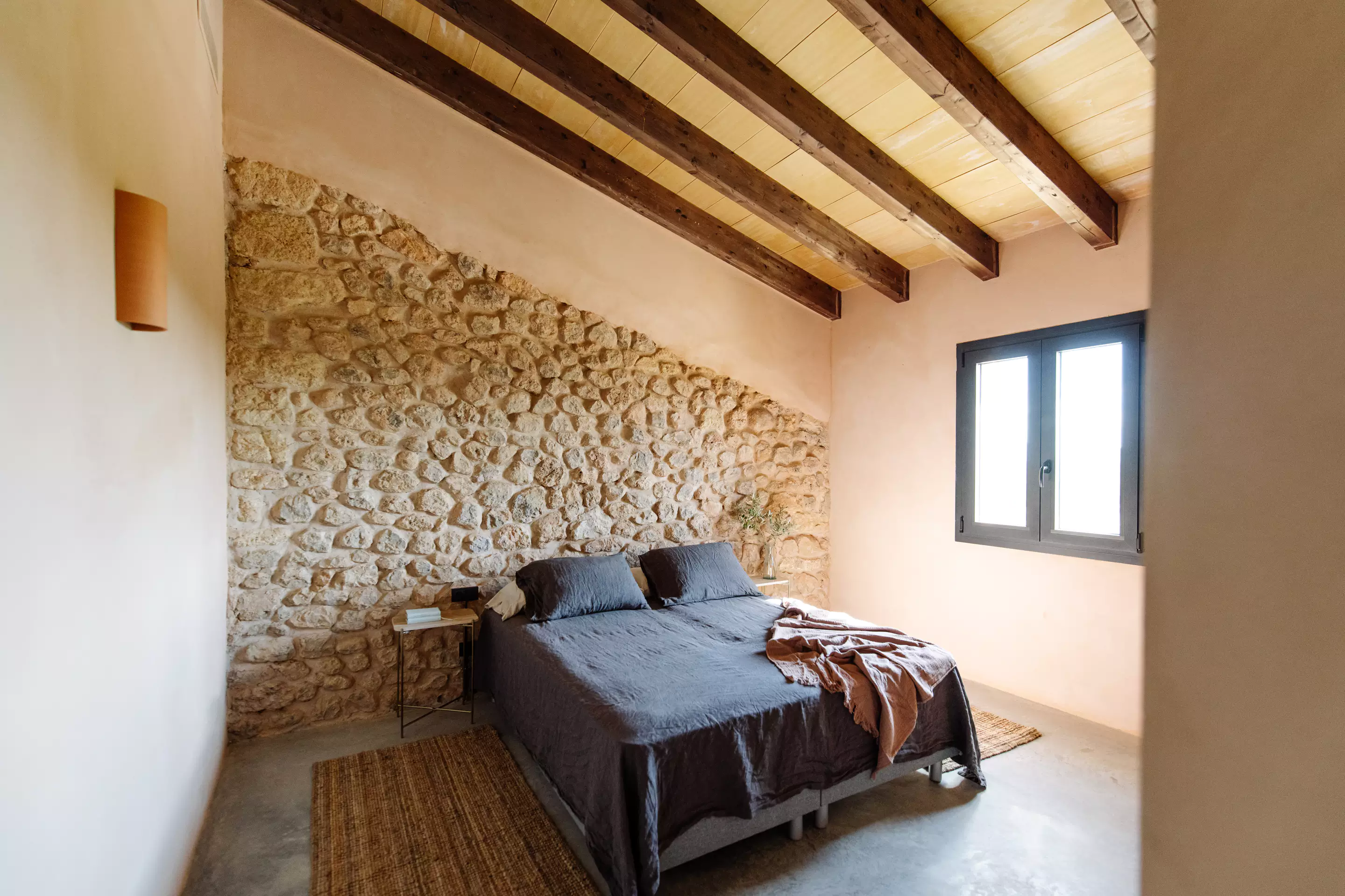 chambre avec poutres et mur de pierres