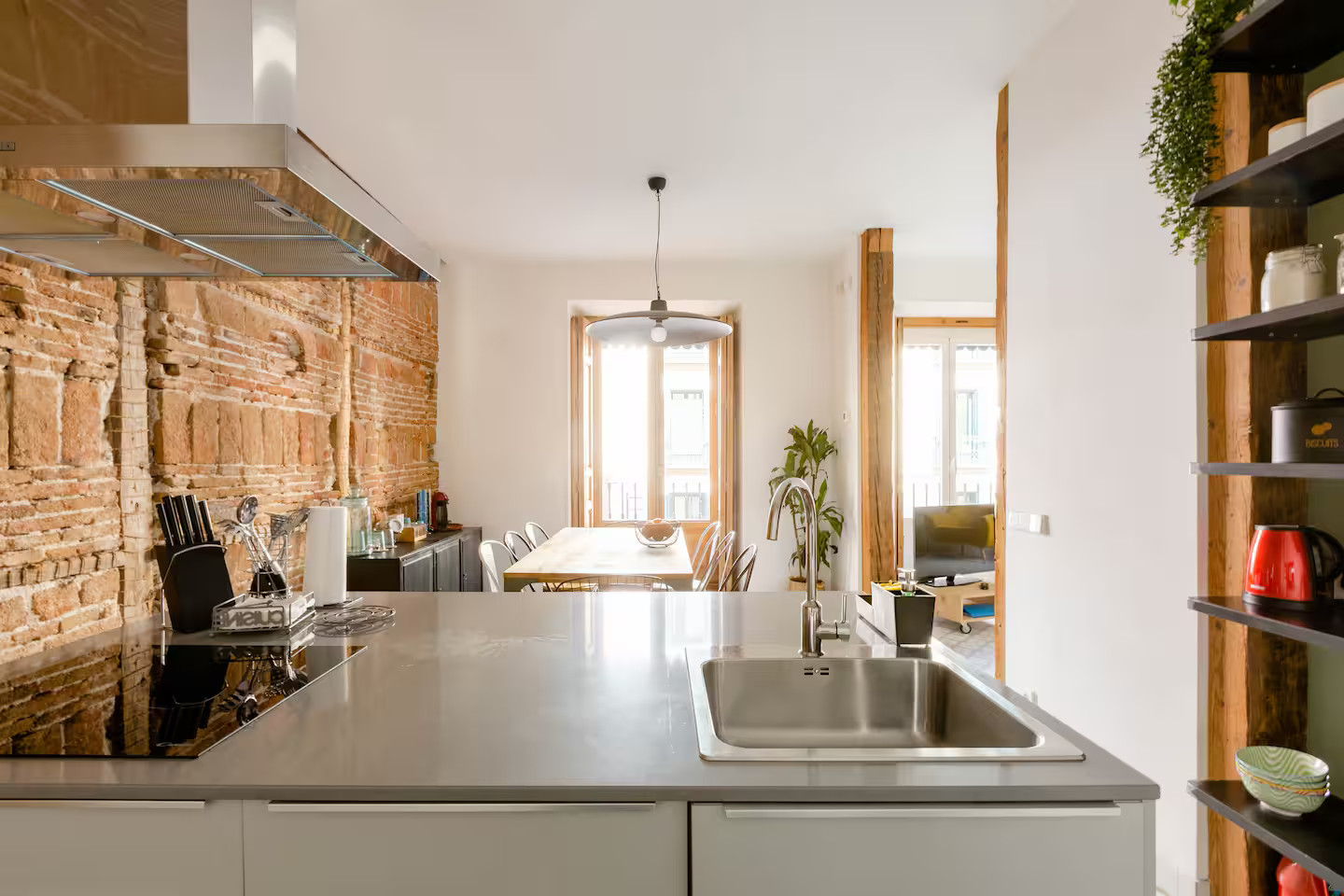 salle à manger et cuisine ouverte mur de briques et poutres appartement Madrid