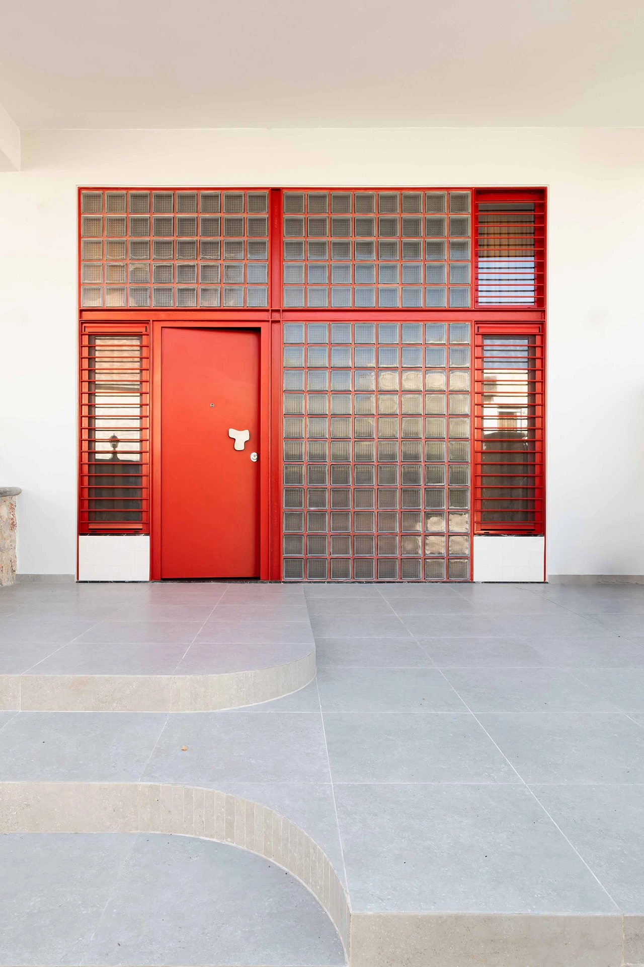façade briques de verre porte en acier rouge appartement rénové 