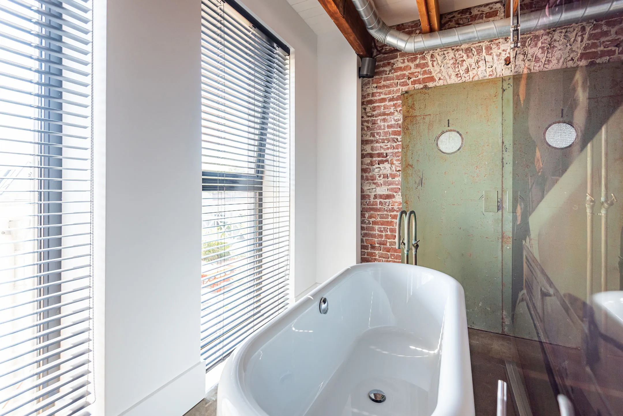 salle de bain poutres et murs briques style industriel dans ancienne usine