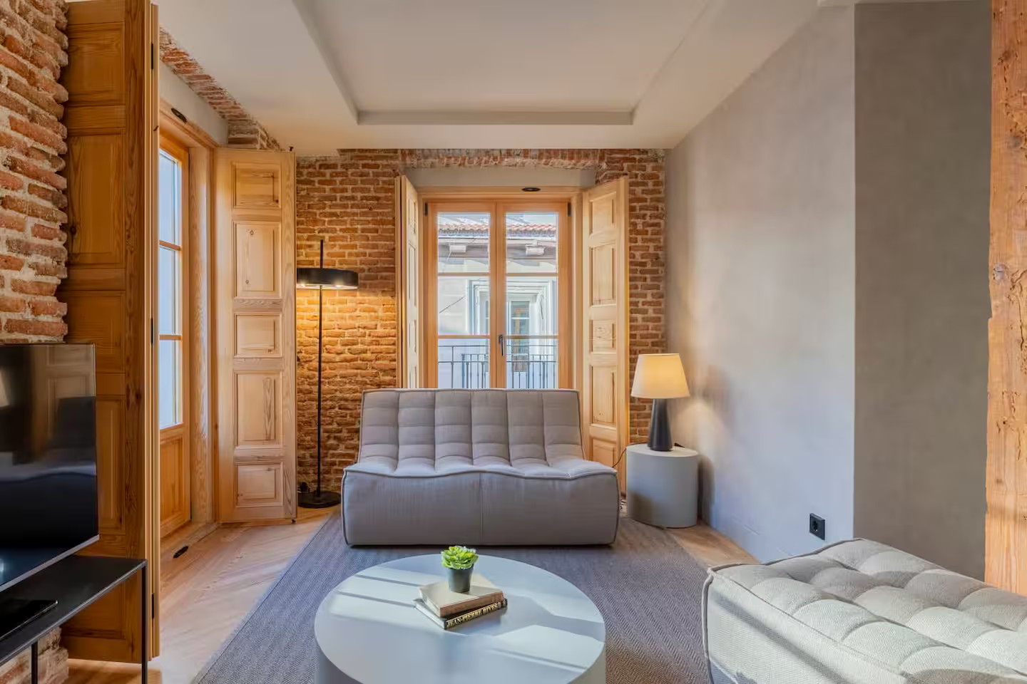 salon studio optimisé en deux-pièces avec murs briques et volets intérieurs salon studio optimisé en deux-pièces avec murs briques et volets intérieurs