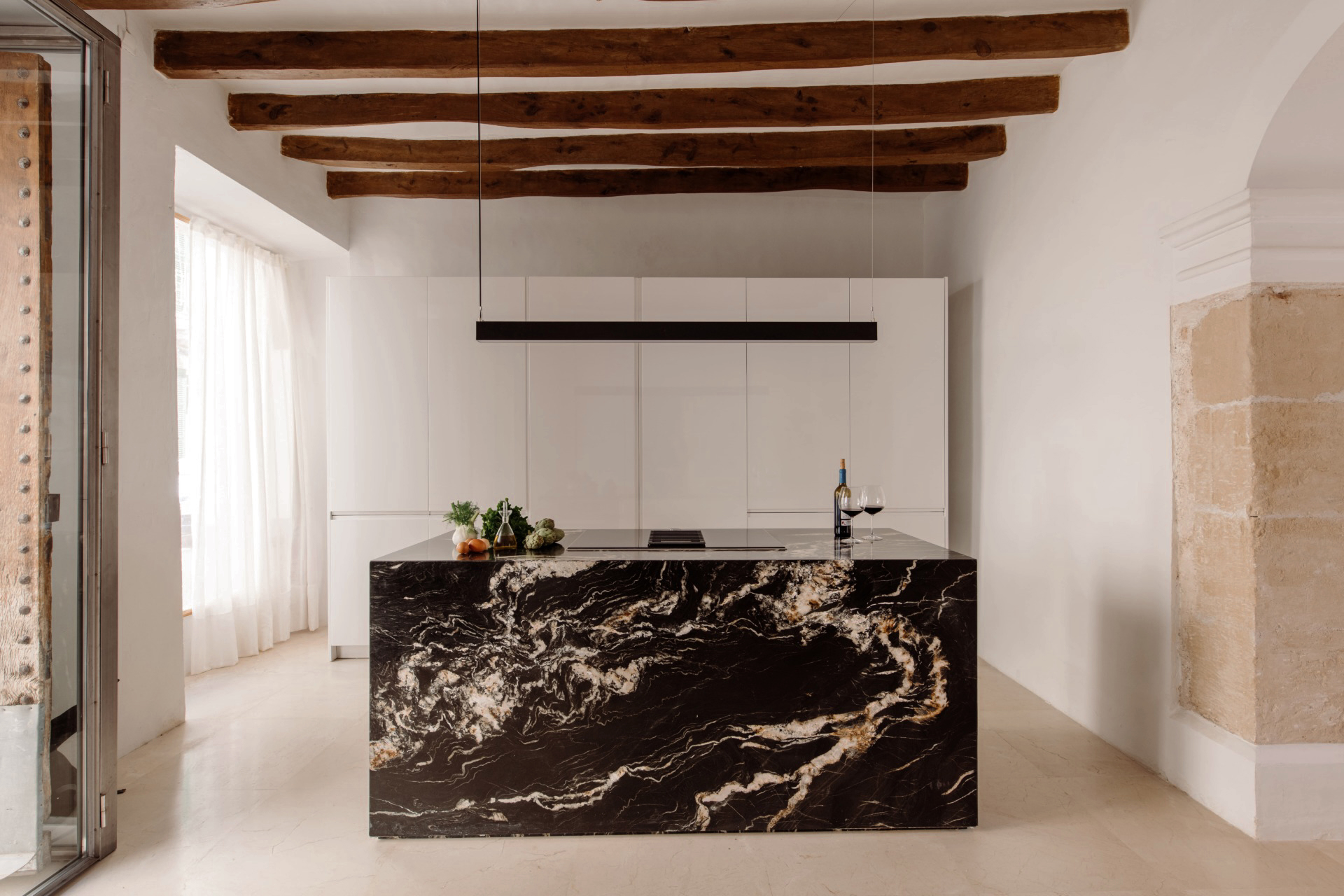 cuisine design blanche avec îlot marbre noir avec poutres décoration contemporaine maison ancienne Majorque