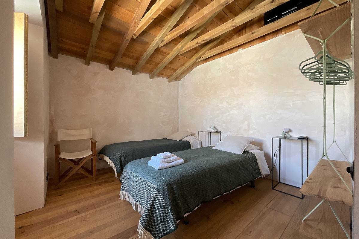 chambre à deux lits décoration minimaliste avec poutres appartement rénové Portugal