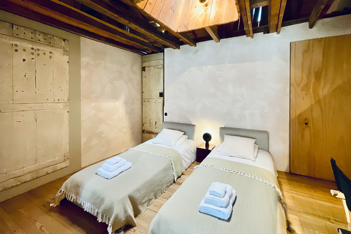 chambre à deux lits décoration minimaliste avec poutres appartement rénové Portugal