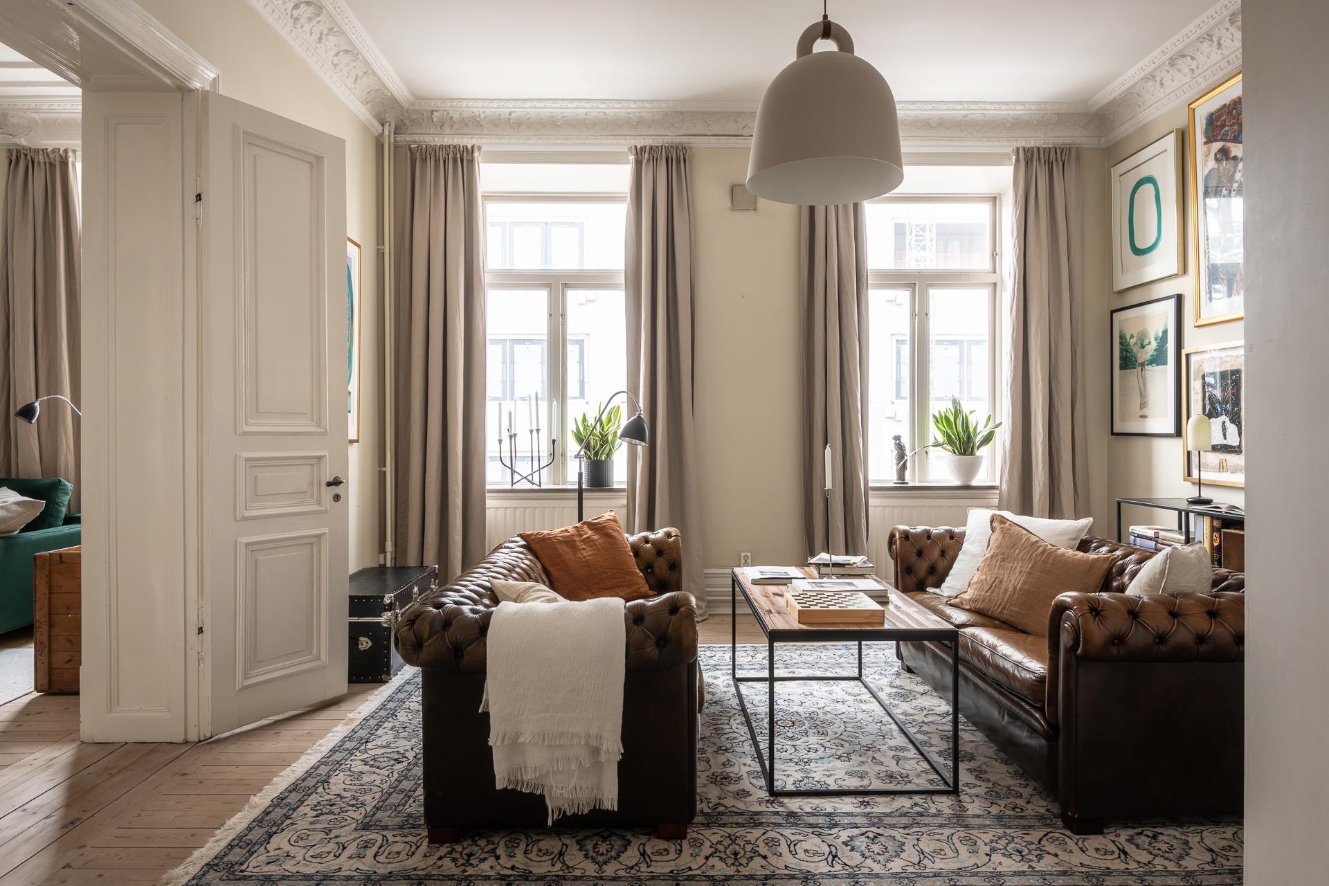 salon avec canapé Chesterfield cuir marron moulures appartement type haussmannien décoration classique chic