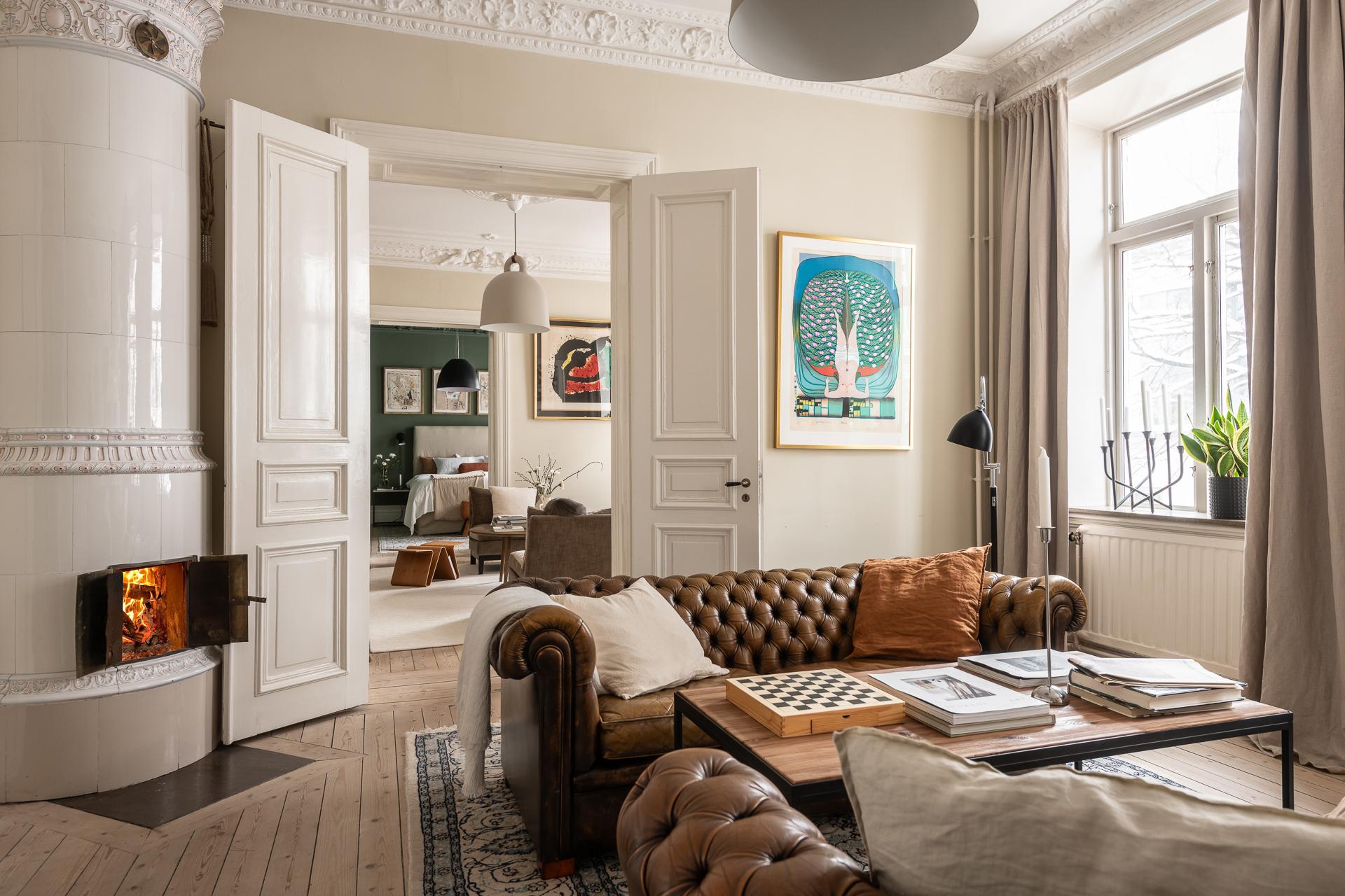 salon avec canapé Chesterfield cuir marron moulures appartement type haussmannien et poêle scandinave décoration classique chic