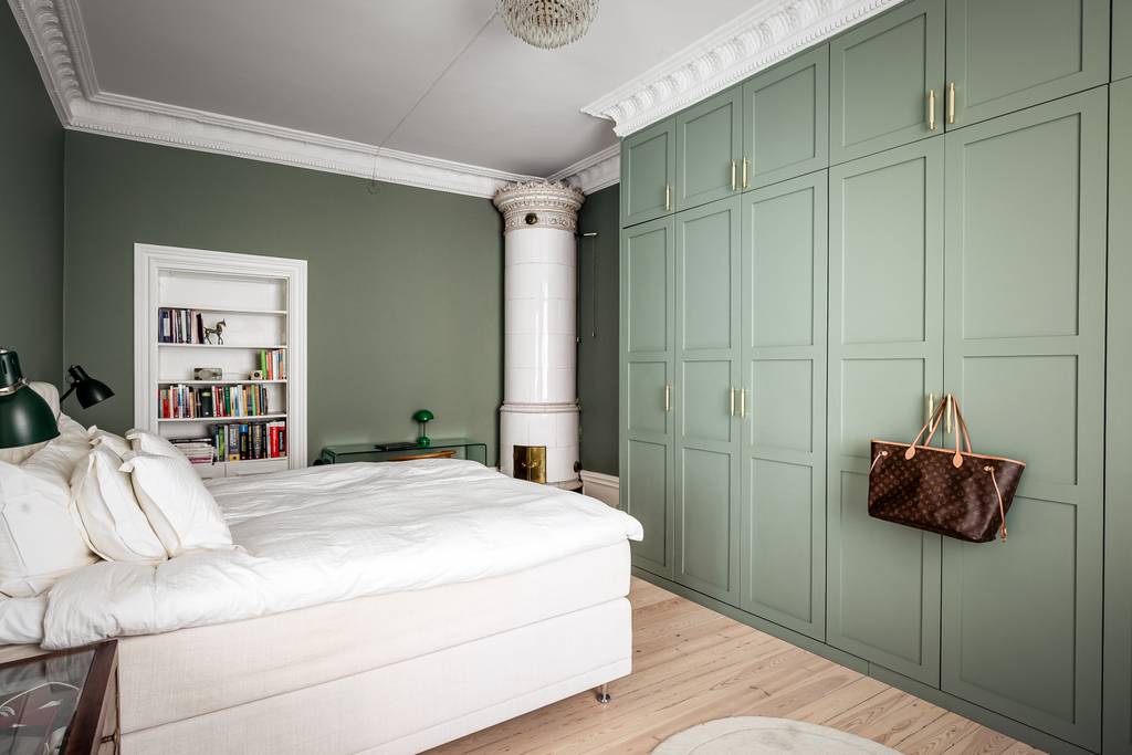 chambre vert sauge avec moulures stucs rosaces et poêle ancien appartement décoration scandinave