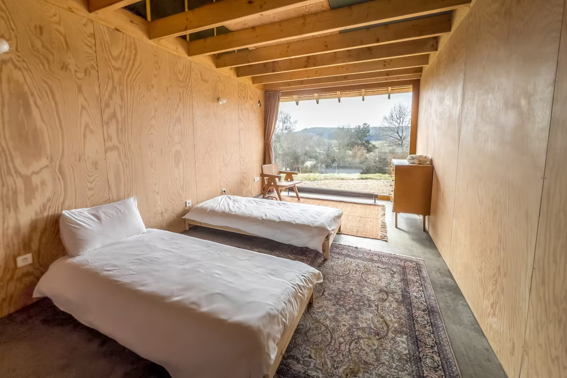 bedroom with two beds beams wood walls bay window
