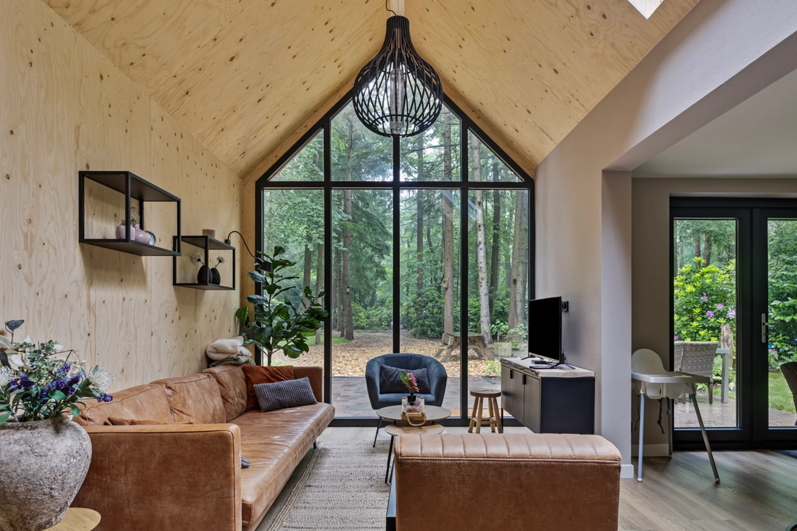 living room with double-height glass gable modern wooden house with lush garden Netherlands living room with double-height glass gable modern wooden house with lush garden Netherlands