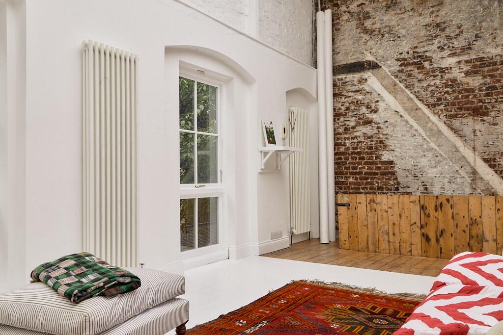 salon murs de briques patinées ancien appartement loft avec verrières du photographe de mode Tim Walker à Londres décoration contemporaine et industrielle 