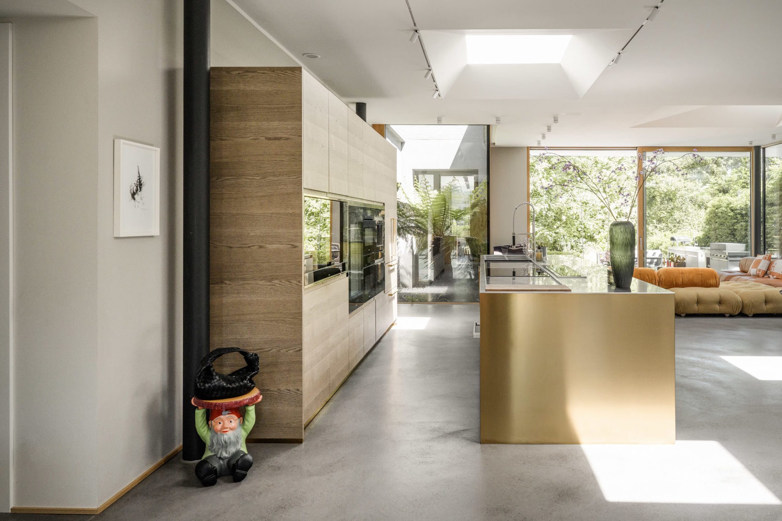 cuisine ouverte bois et laiton et salon décoration design et contemporaine sol béton ciré grandes baies vitrées maison d'architecte