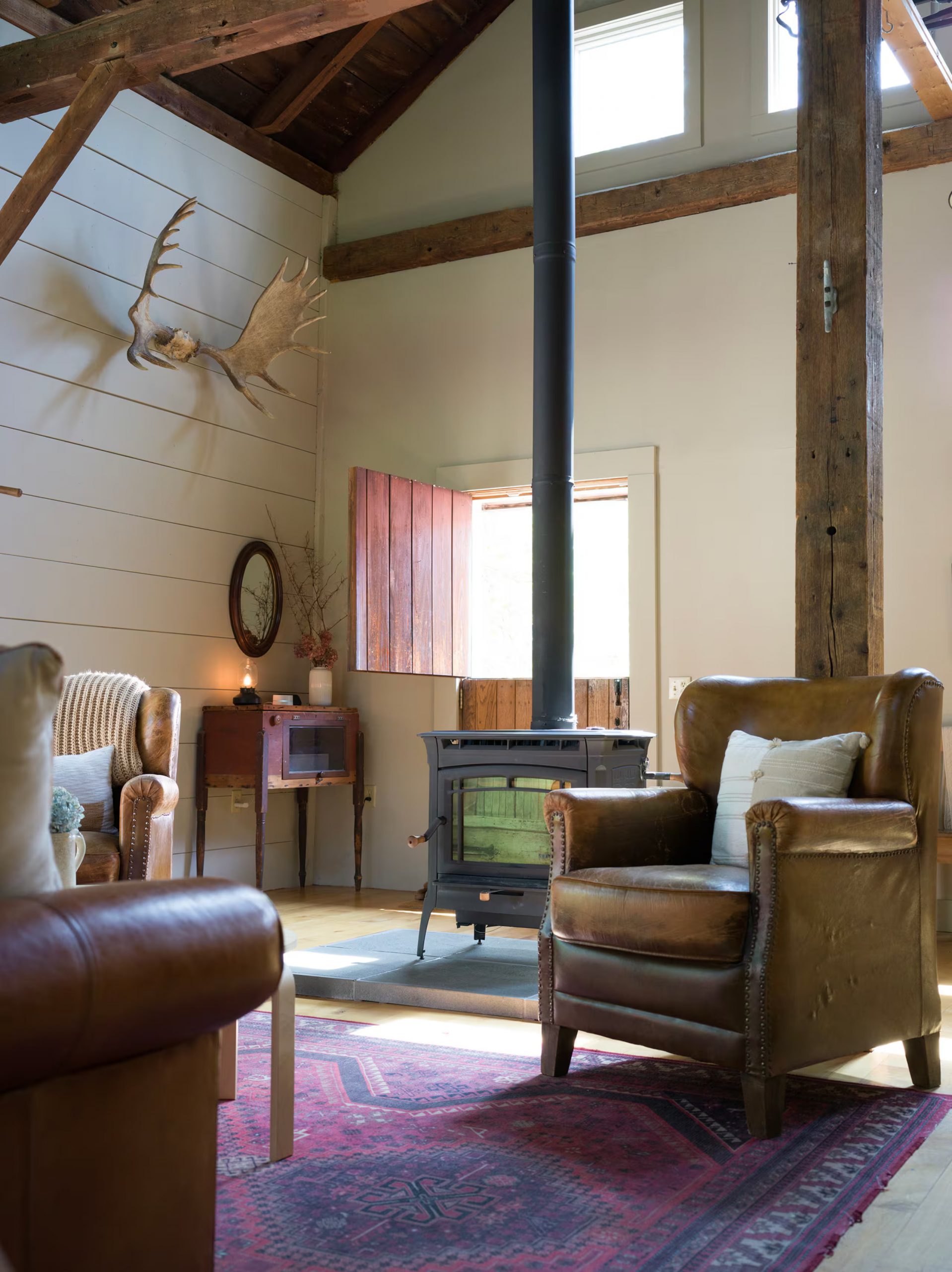 salon avec fauteuils club cuir et poêle grange rénovée du 19e siècle